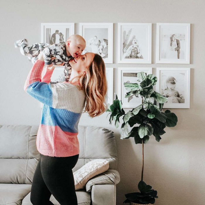 White picture frame gallery wall behind happy mother and baby