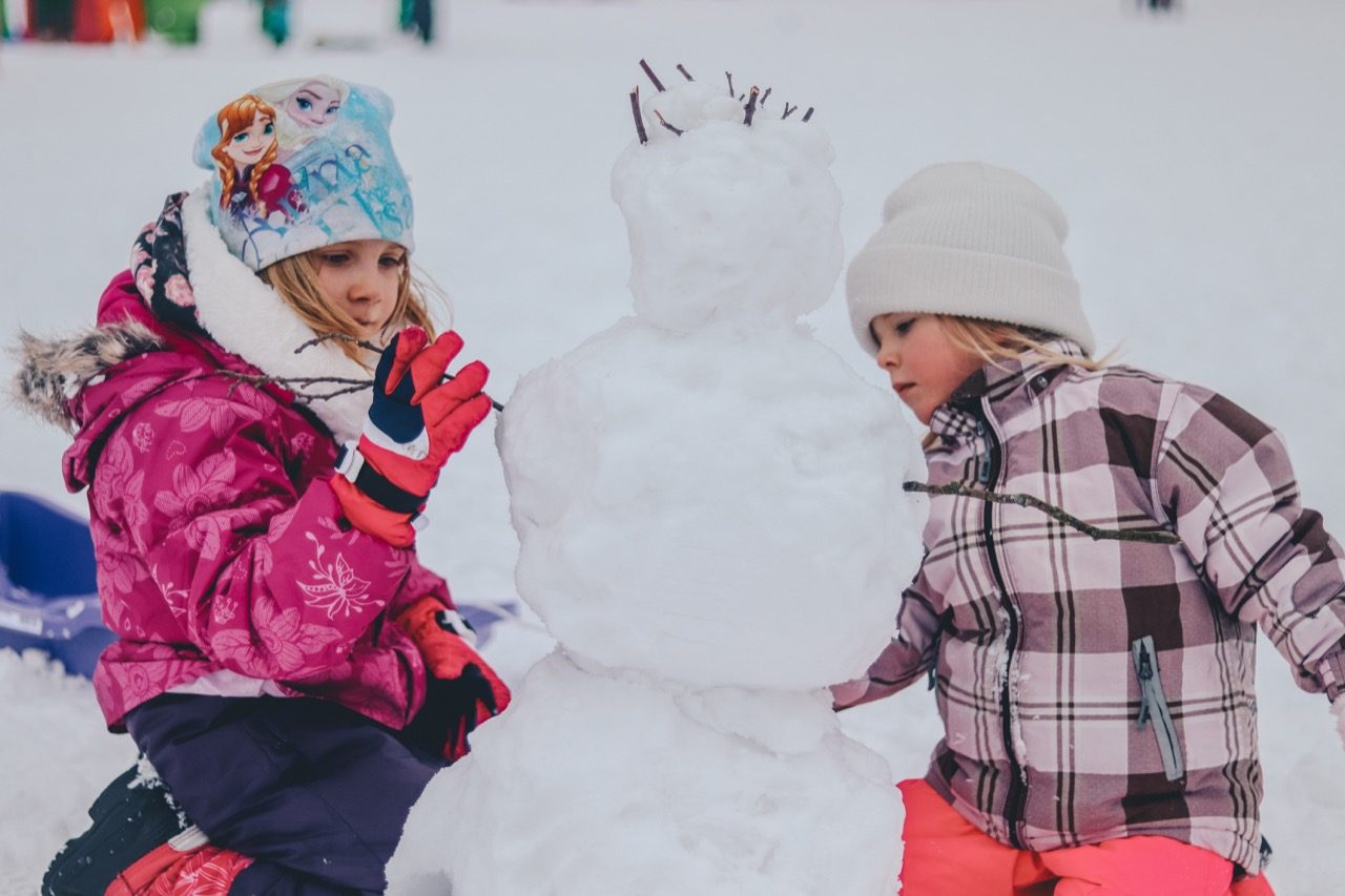 Two kids building a snowman.