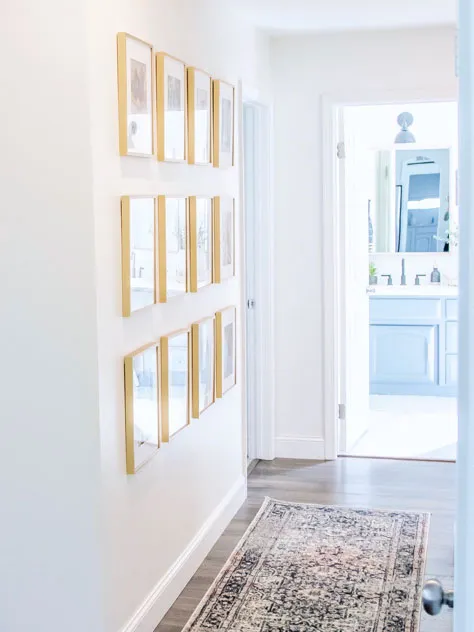 wall gallery of gold metal frames in white hallway