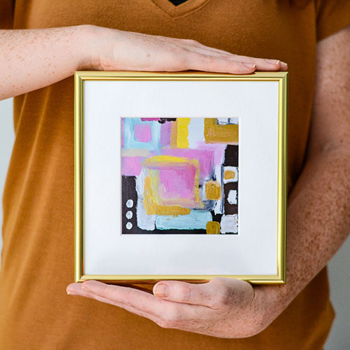 hands holding frame of painted art