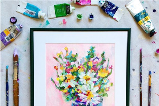 Paints and brushes around framed painting