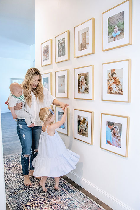 smiling mother with two children with gold frames hanging in hallway