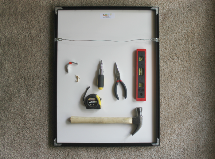 Picture frame with level, hammer, pliers, and measuring tape