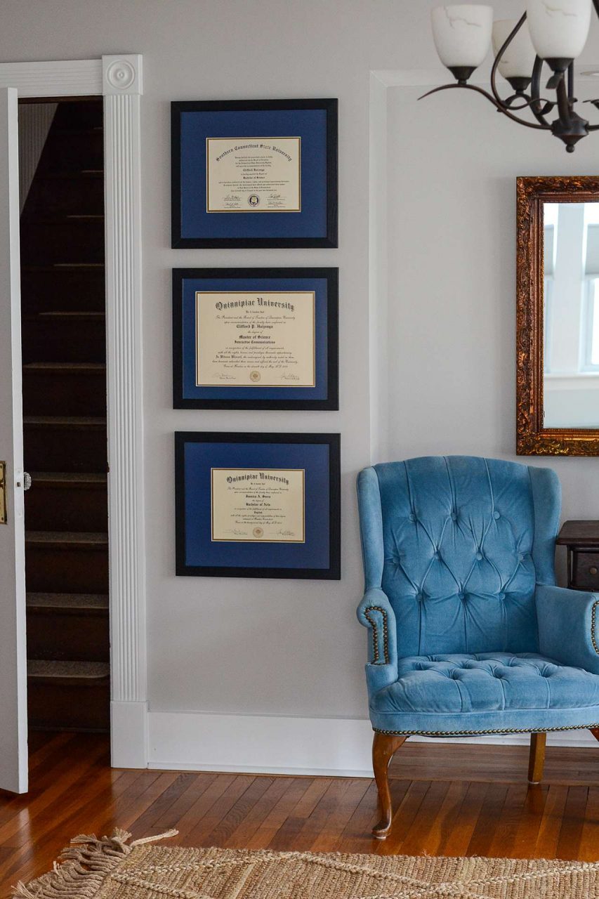 Framed diplomas on a wall with chair