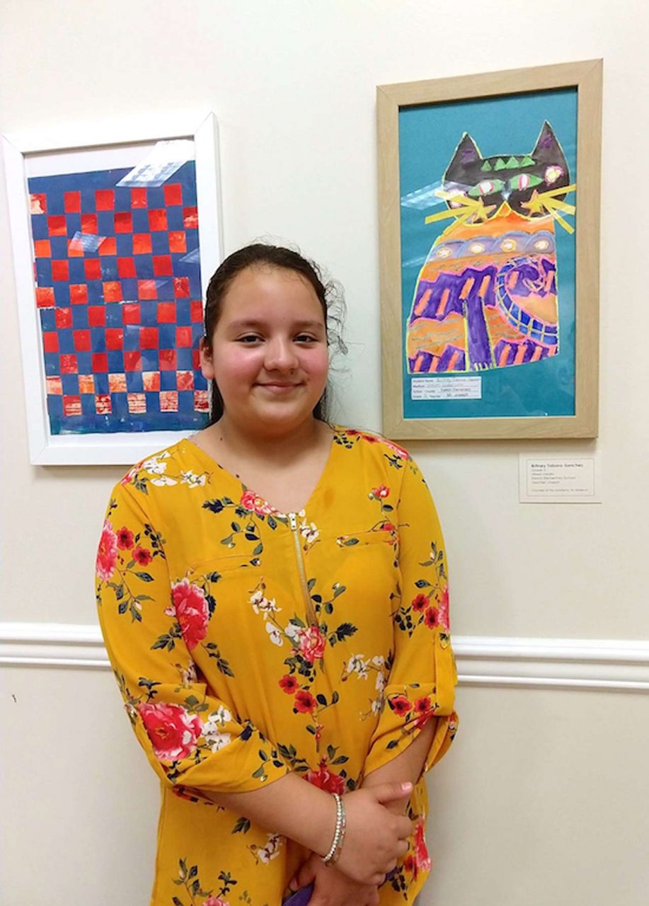 Young artist with painted and framed art on wall