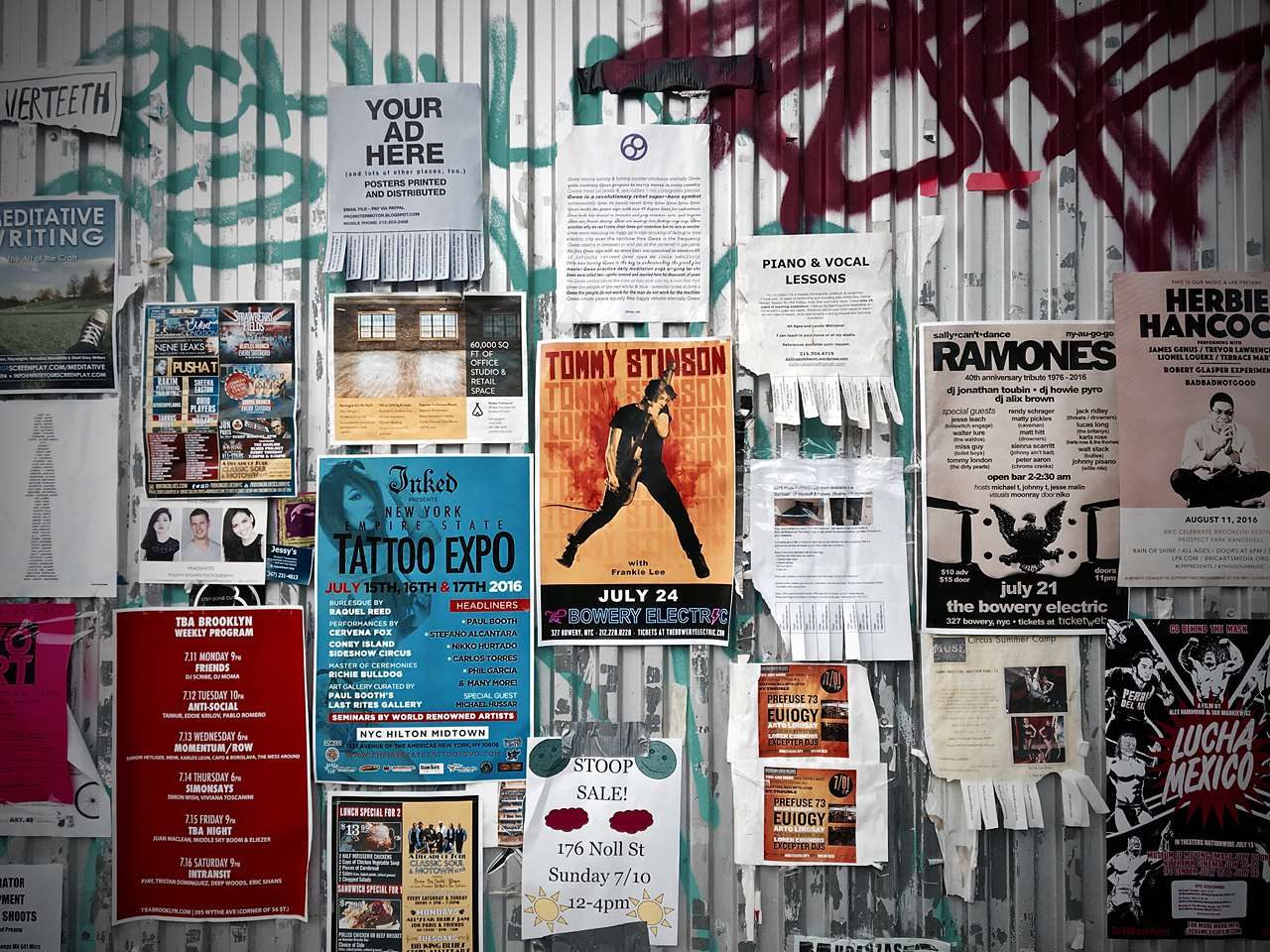 Printed flyers covering graffitied steel wall