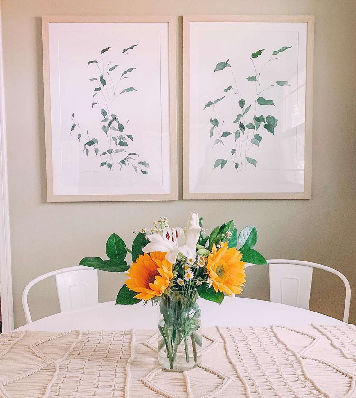 Side-by-side picture frames in front of table with flowers