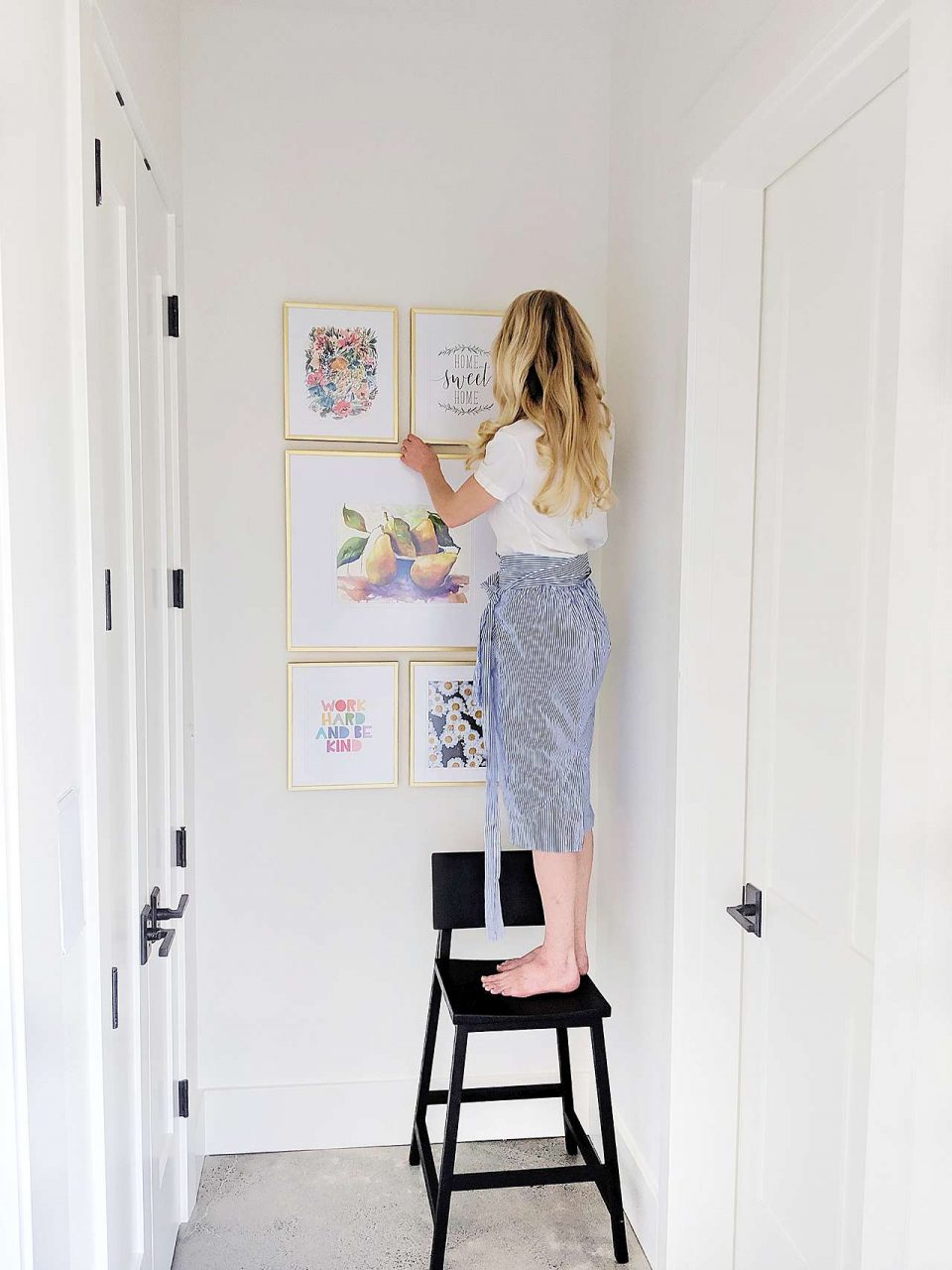 woman hanging gold picture frames