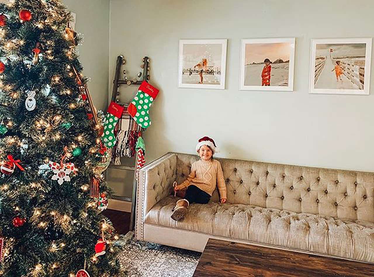Holiday picture frames with child on couch next to decorated tree