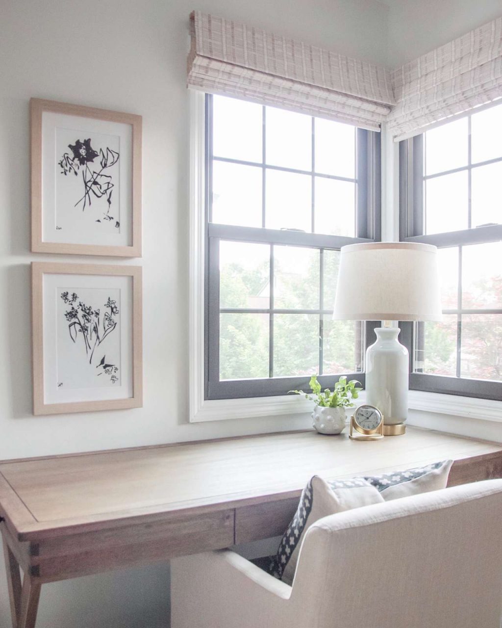 Simple stacked picture frames above wooden desk next to bright windows