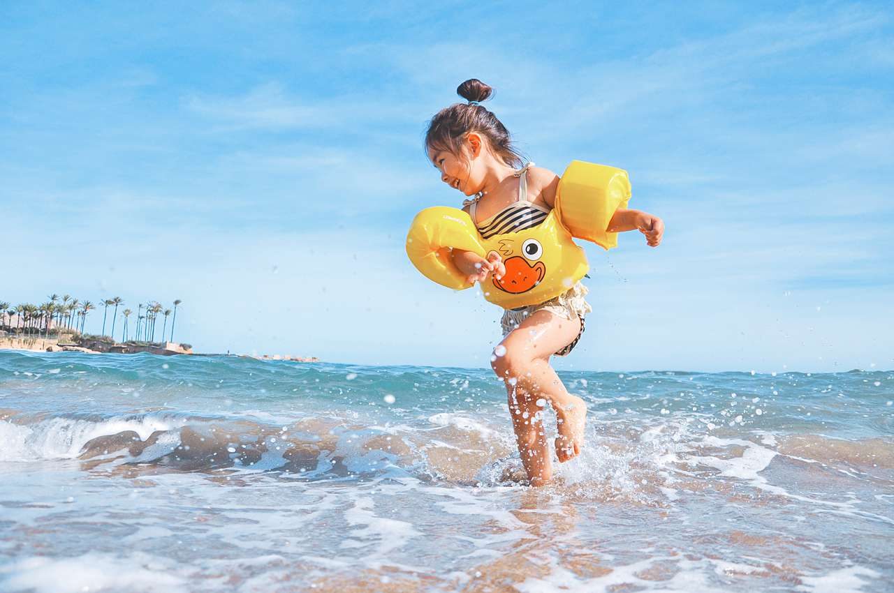 little girl splashing in ocean at beach