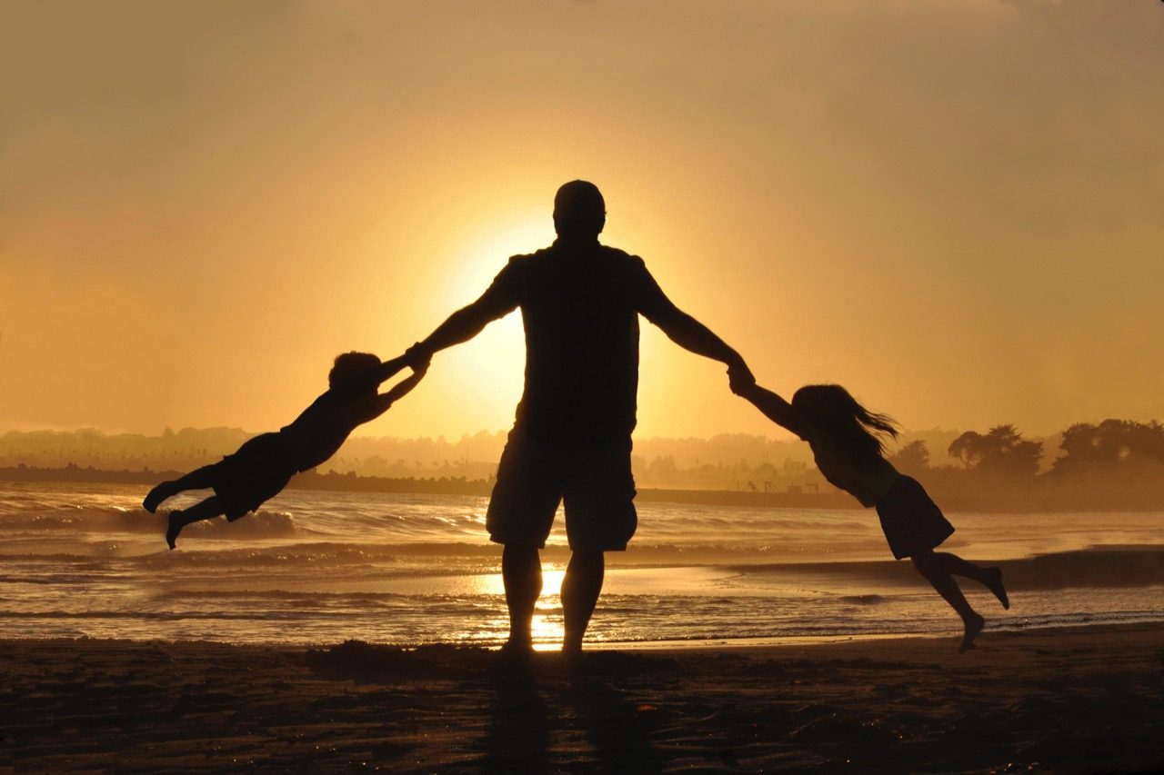 father and children silhouette on beach