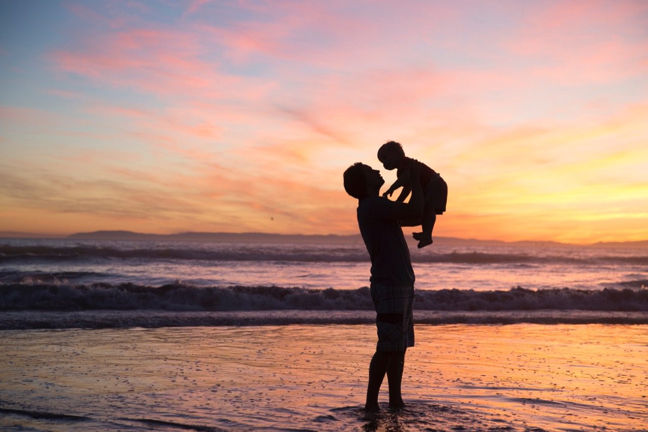 man and child silhouette on beach