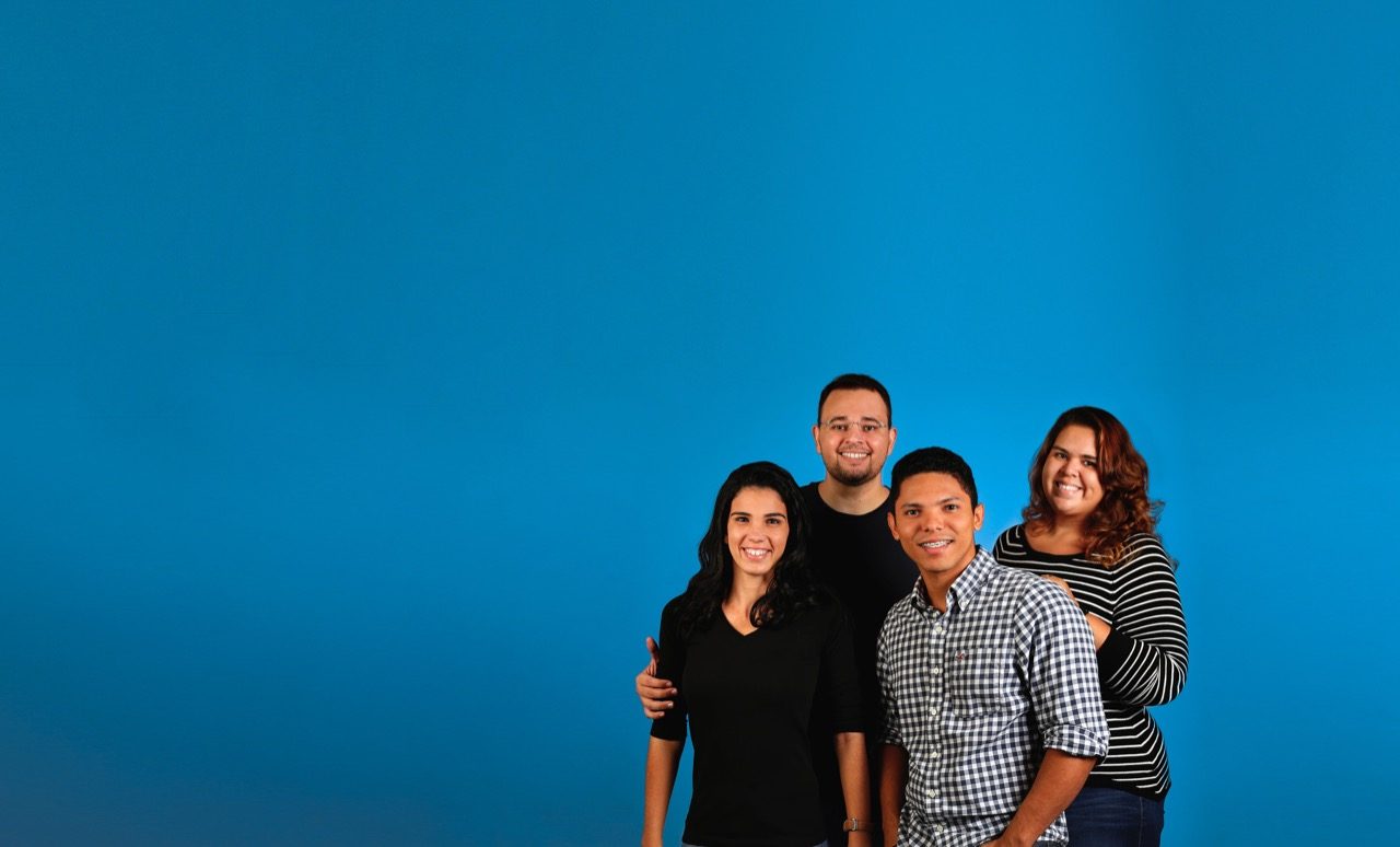 Family posing for picture in front of plain backdrop. 