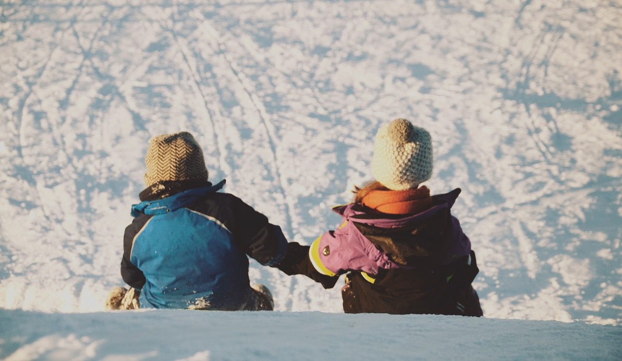 two kids sledding down slope