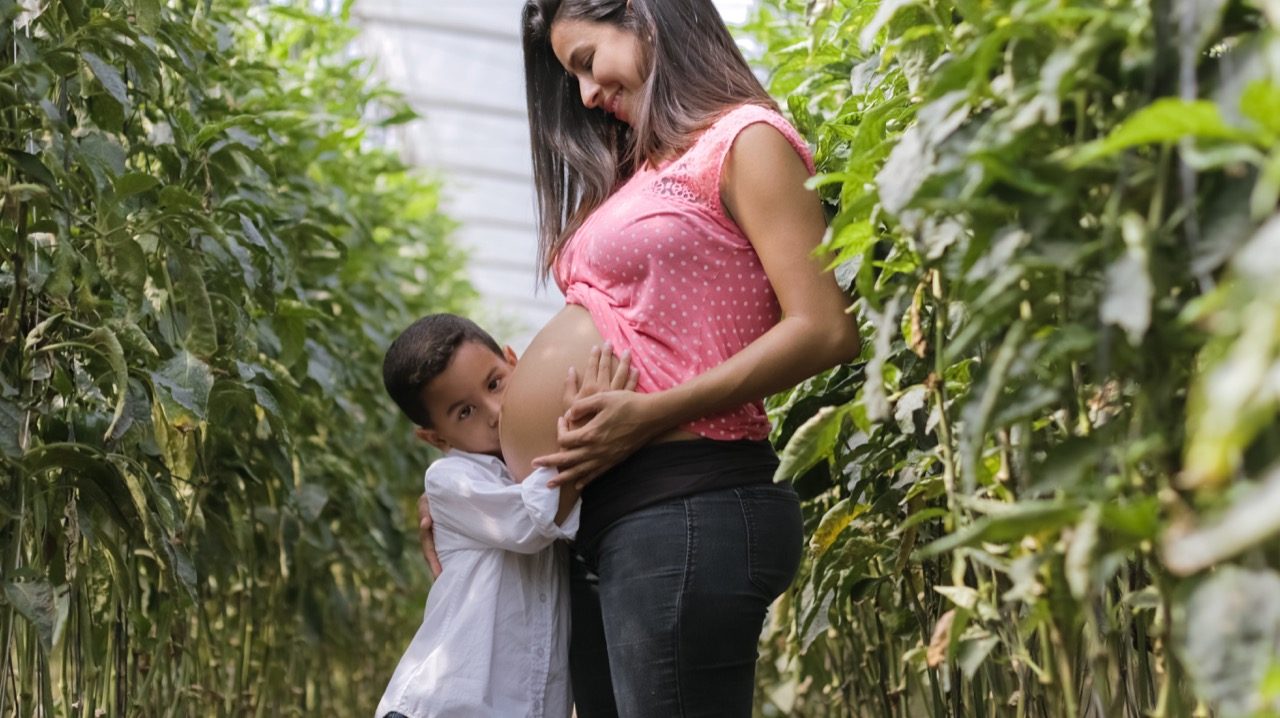 Son kissing his mothers pregnant belly. 