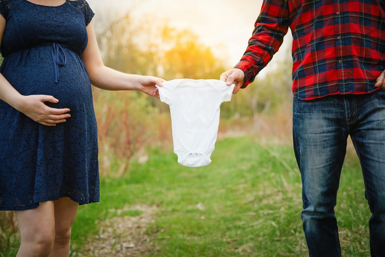 Two parents holding baby's clothing