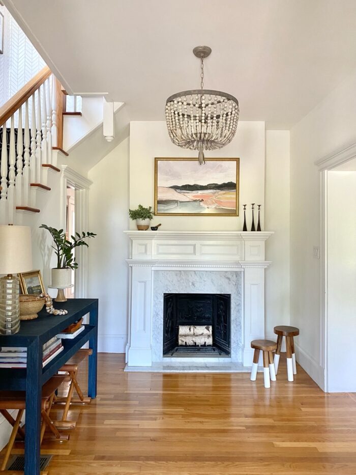 A framed landscape painting over a fireplace. 