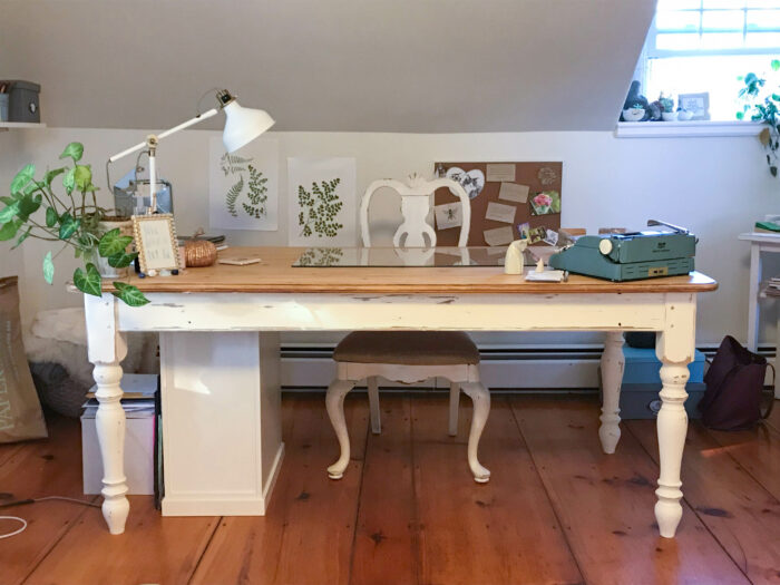 Cottagecore style: Vintage white desk and chair in an office with art prints and typewriter.