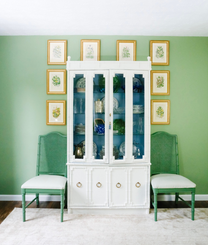 Green room with white dresser and gold framed pictures.