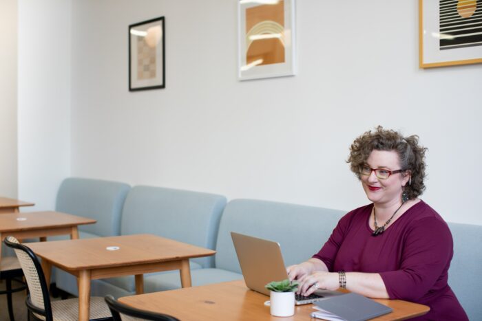 Woman working on a laptop in a waiting room.