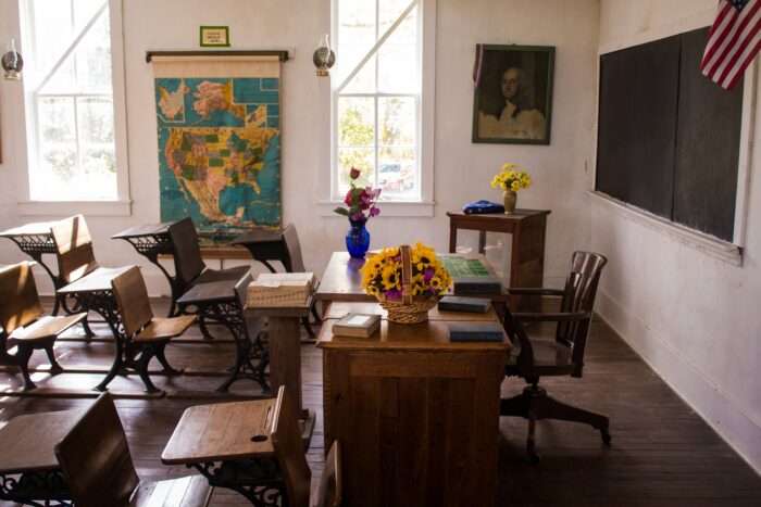Vacant classroom with desks and framed art prints.