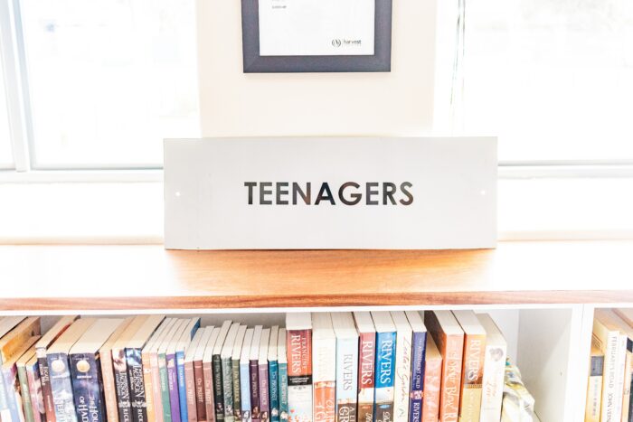 Close-up image of library book shelf with sign on shelf.