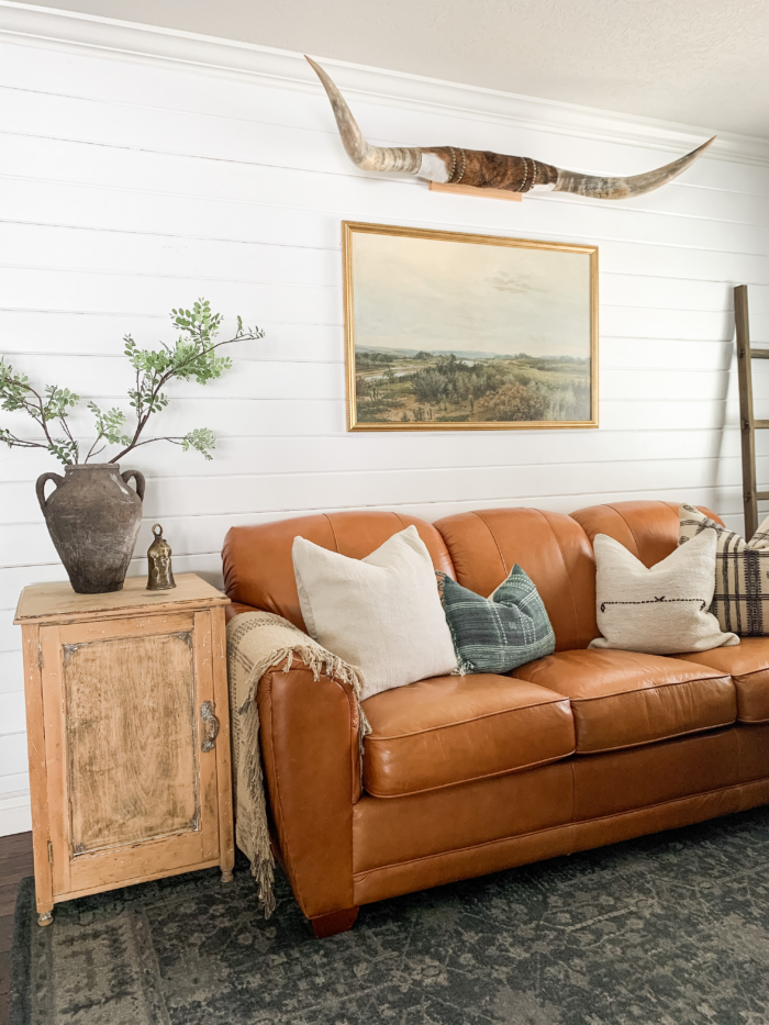 Office decor - Leather sofa in a living room with framed art print.