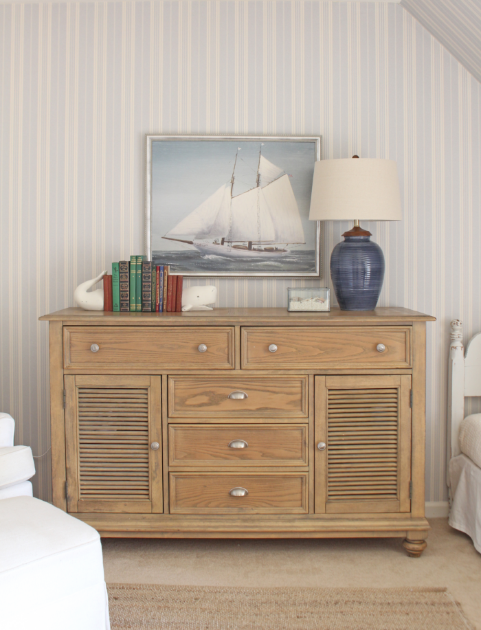 Nautical theme room with framed boat print and a blue lamp.