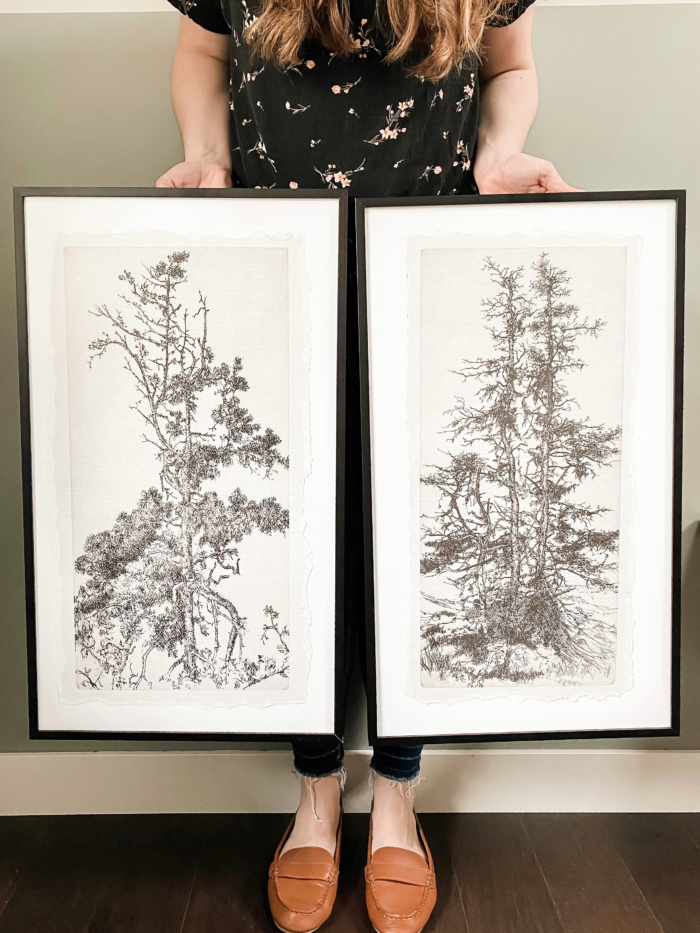 A customer holding black picture frames with illustrations 