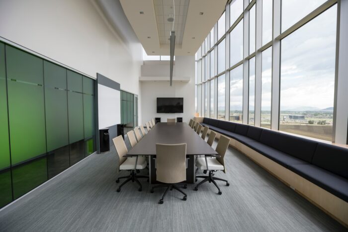 Large conference room design with green accent wall and big windows.