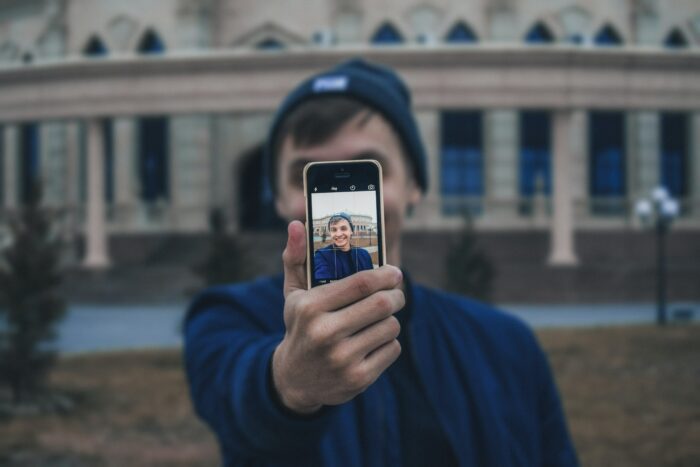 How to Take Professional Headshots: Must-Have Tips 1 How to take professional headshots: Man taking a selfie outdoors.