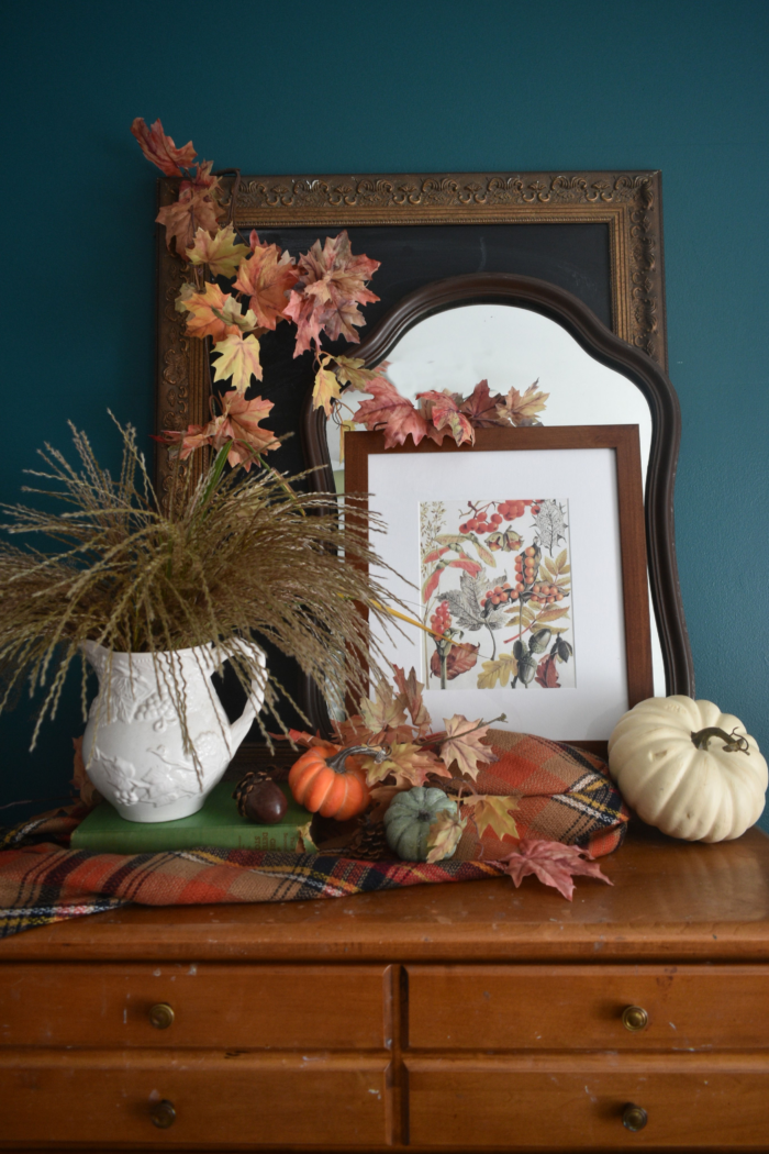 Cozy fall interior with pumpkins and a framed art print.