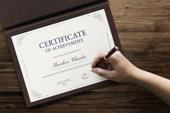 Someone signing an achievement certificate on a desk 