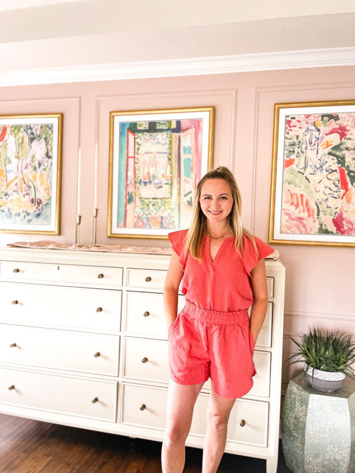 Artist standing in front of framed art prints.