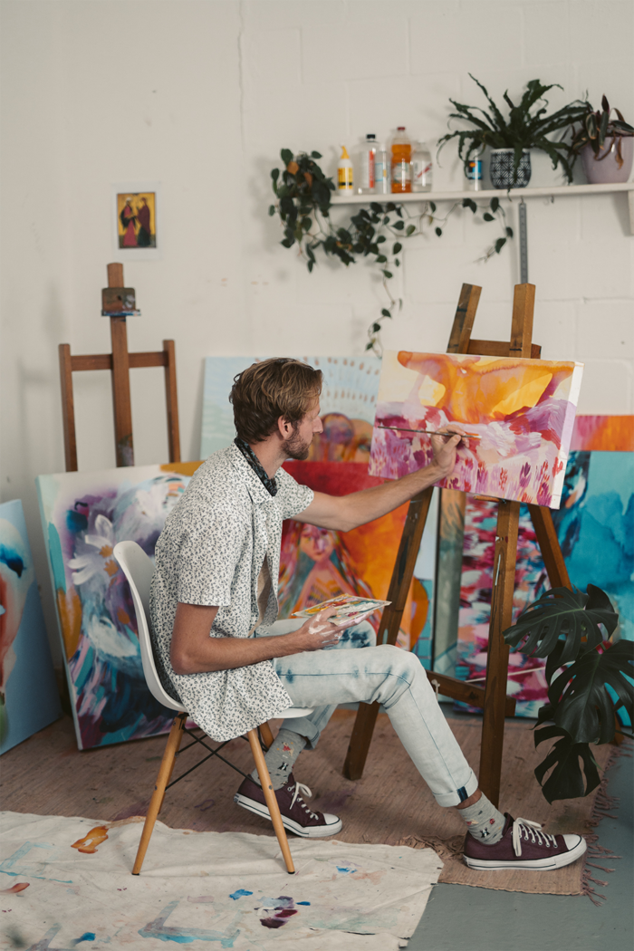 selling art on Etsy: A man painting in his artist studio for his Etsy store