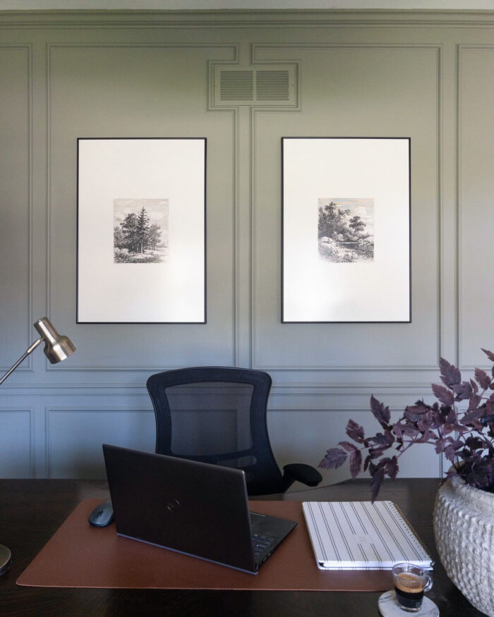 An office with framed art prints above a desk.