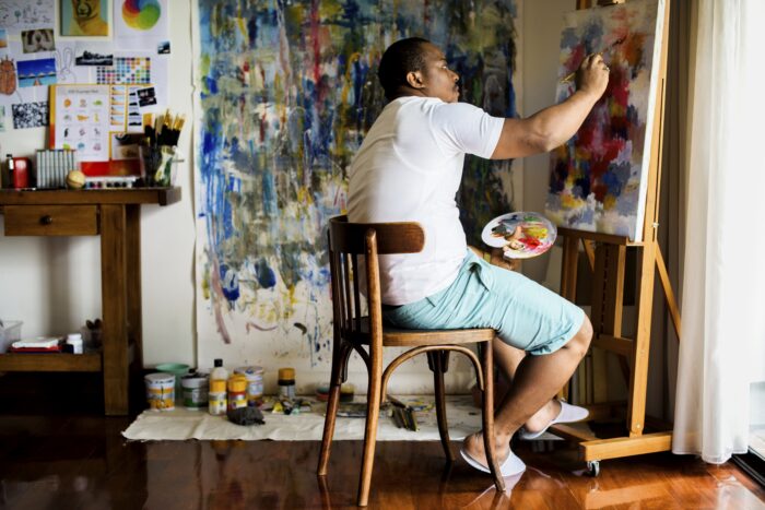 selling art on Etsy: A man painting in a studio for his Etsy store
