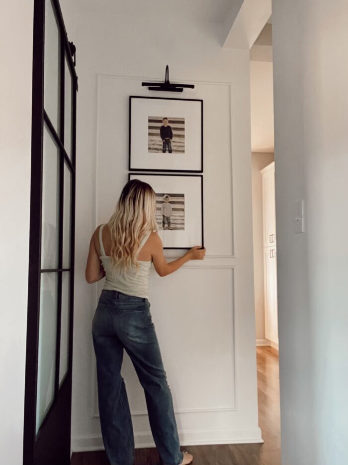 A customer hanging framed photos on the wall 