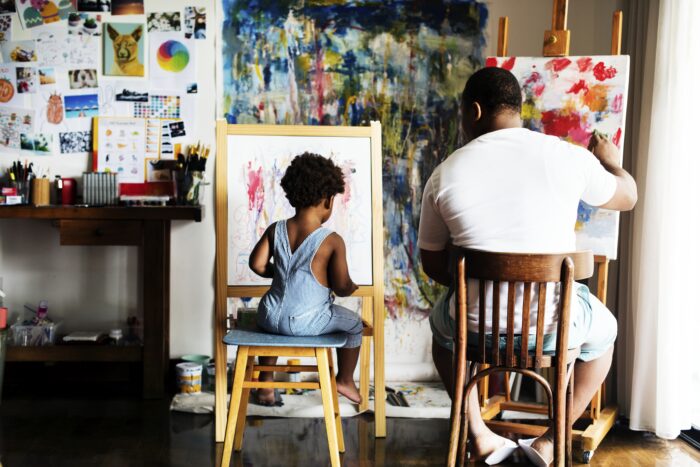 A man teaching a child how to paint in his studio