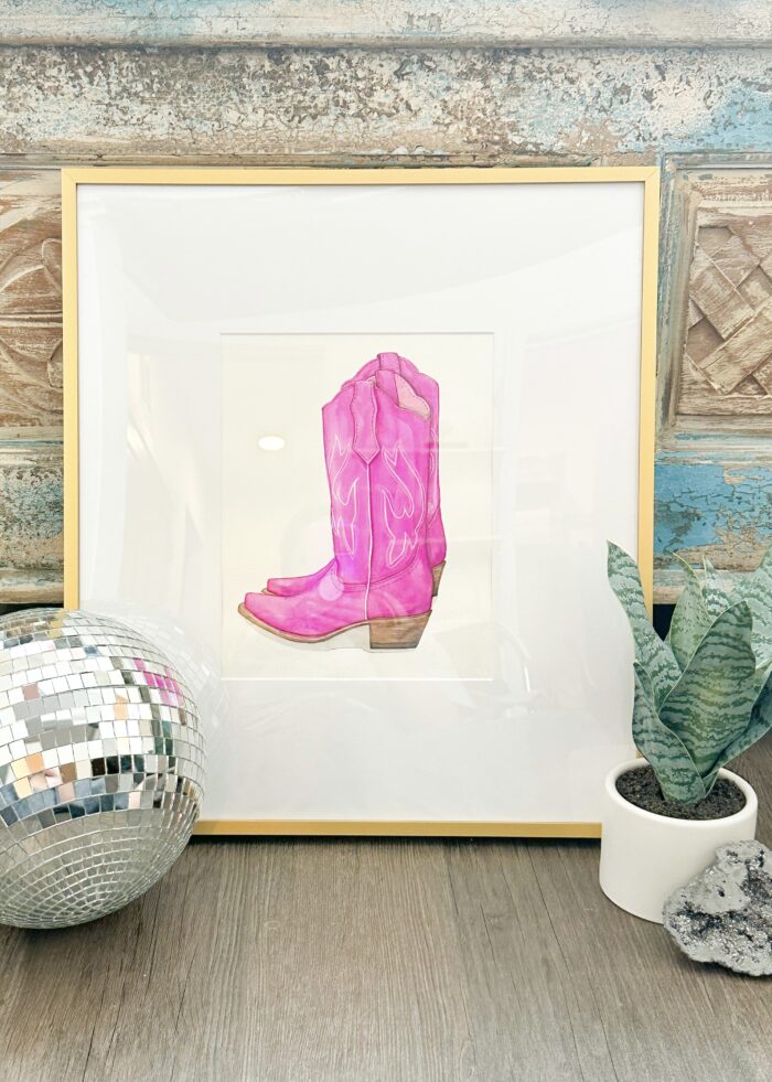 A framed print of a pink boot