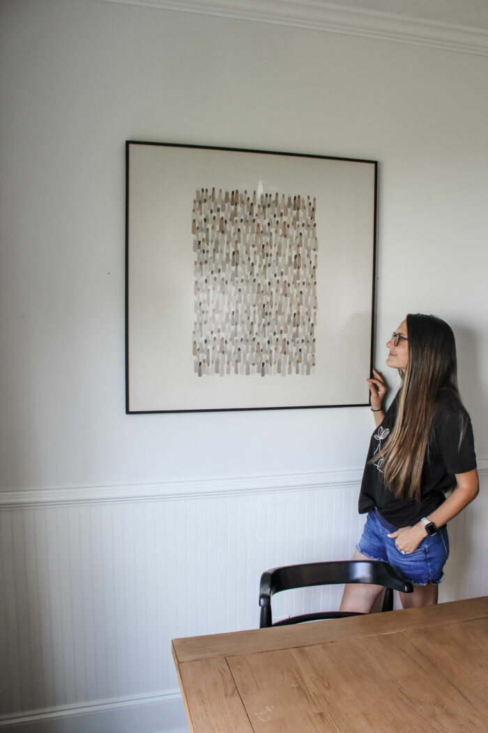 Save Money on Custom Framing: Homeowner next to her hung picture. 