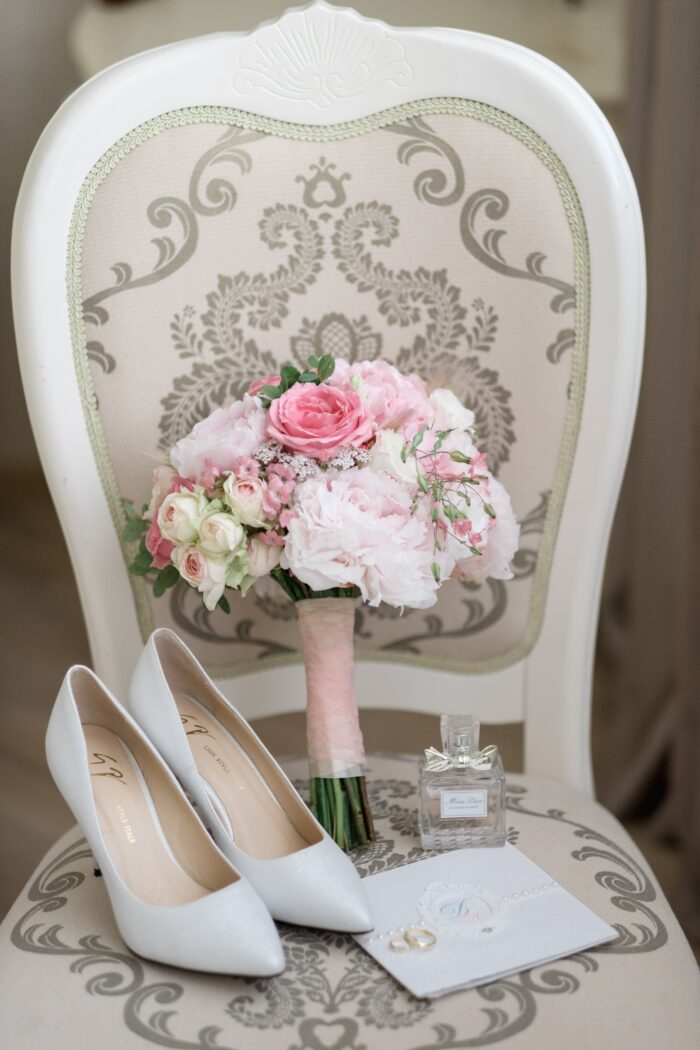 The Ultimate Wedding Photography & Display Guide: A chair with bridal shoes, rings, perfume, flower bouquet, and written wedding vows. 