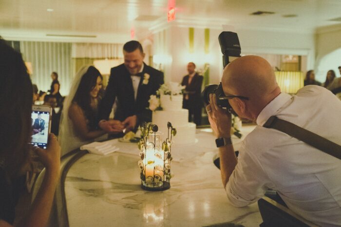 The Ultimate Wedding Photography & Display Guide: A wedding photographer captures a newly wed couple cutting cake. 