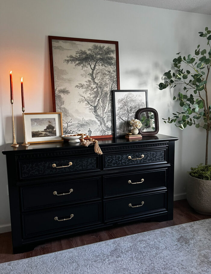 A big picture frame with oversized art on a dresser