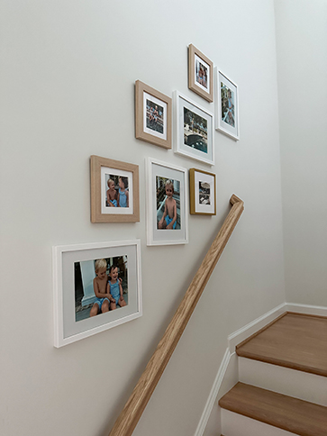 framed family photos above a stair rail