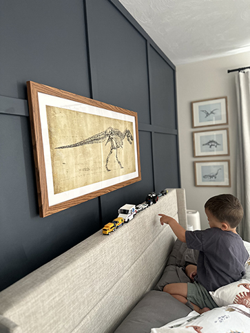 A framed T-rex print in a boys room