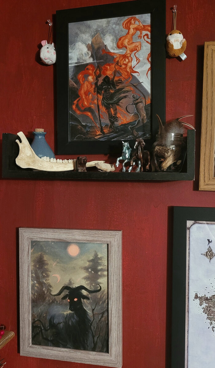 Framed fantasy art on a dark red wall