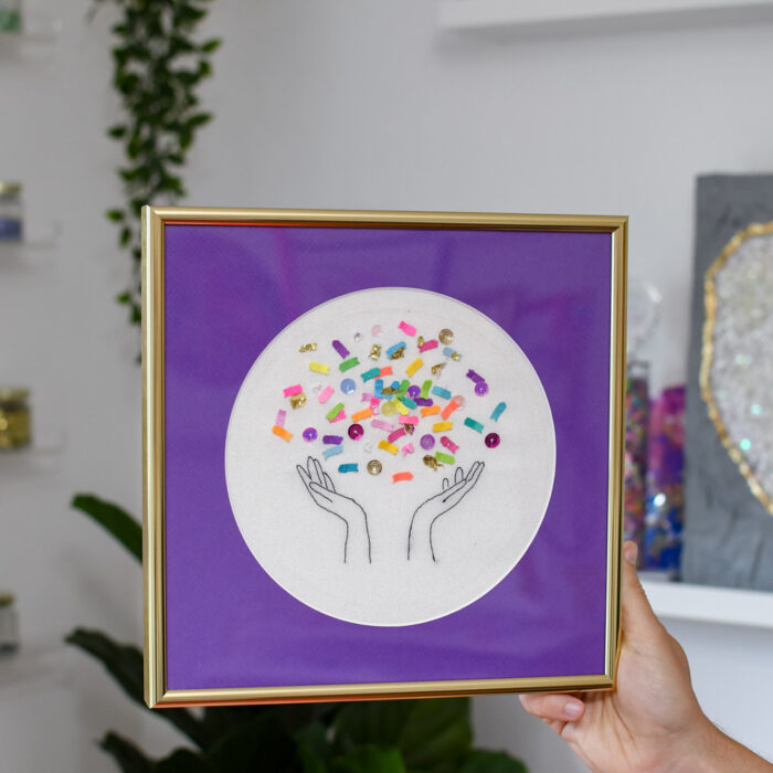 an embroidery piece with an oval matboard opening in a square frame