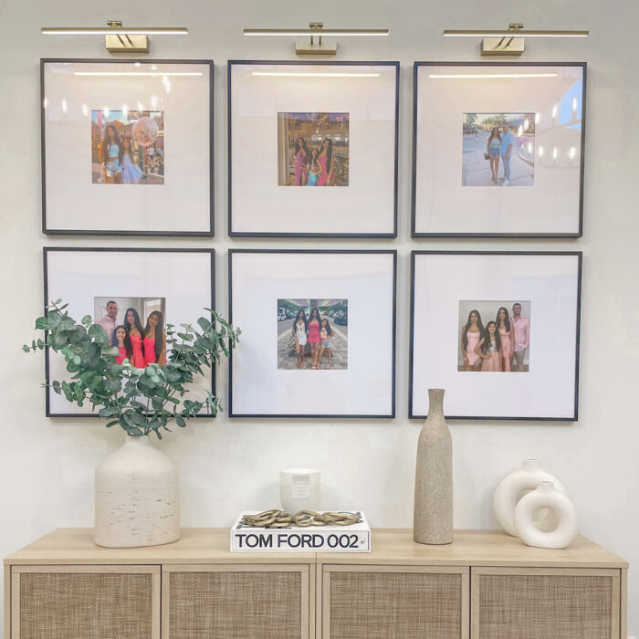 A decorative hallway with a 2x3 grid gallery wall of family photos in square frames